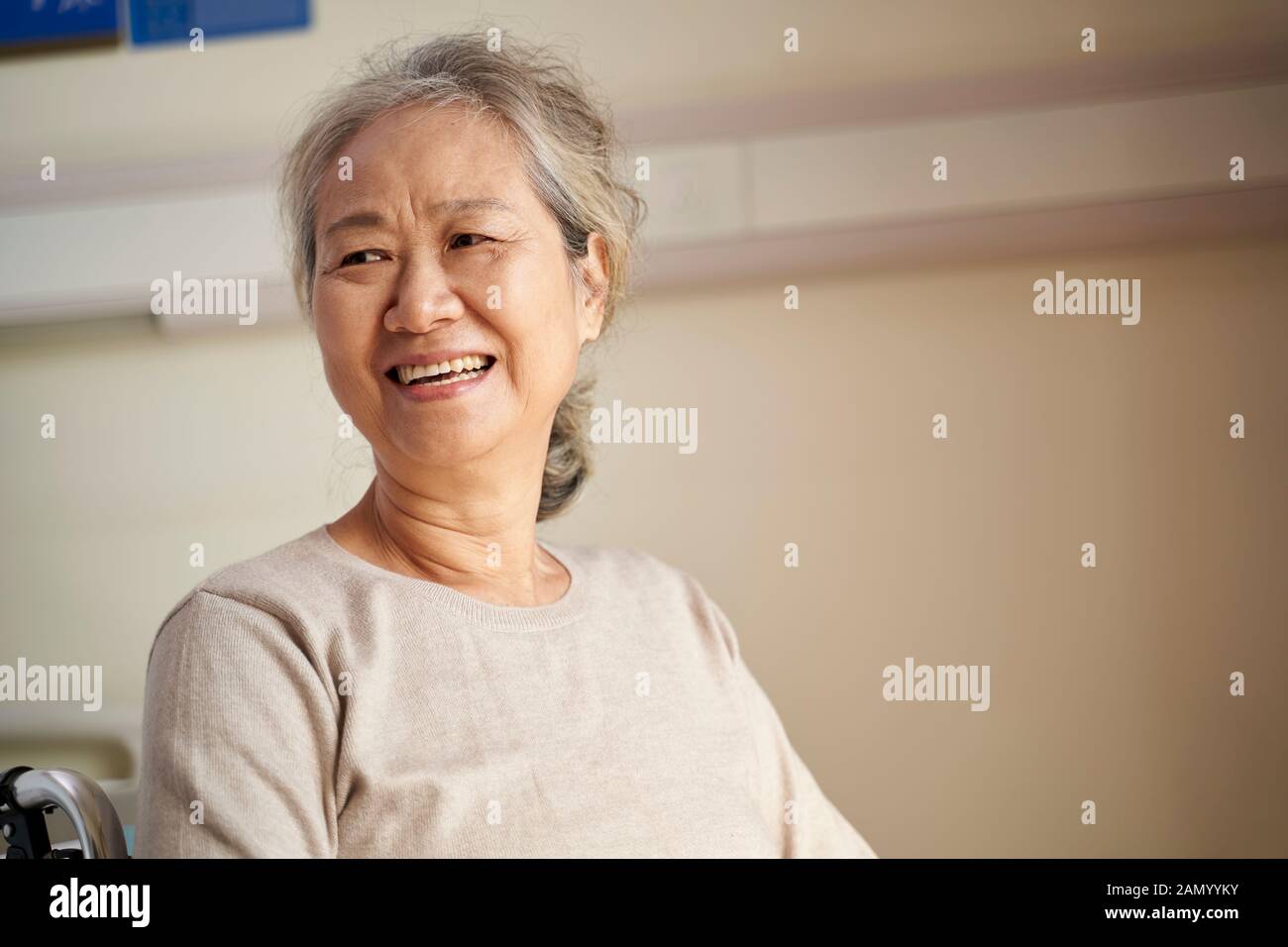 ritratto di una vecchia donna asiatica seduta in sedia a rotelle in casa di riposo, felice e sorridente Foto Stock