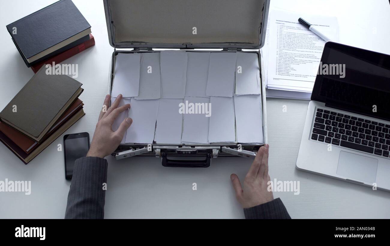 Uomo che apre la valigetta con documenti invece di denaro, frodi aziendali, contraffatti Foto Stock
