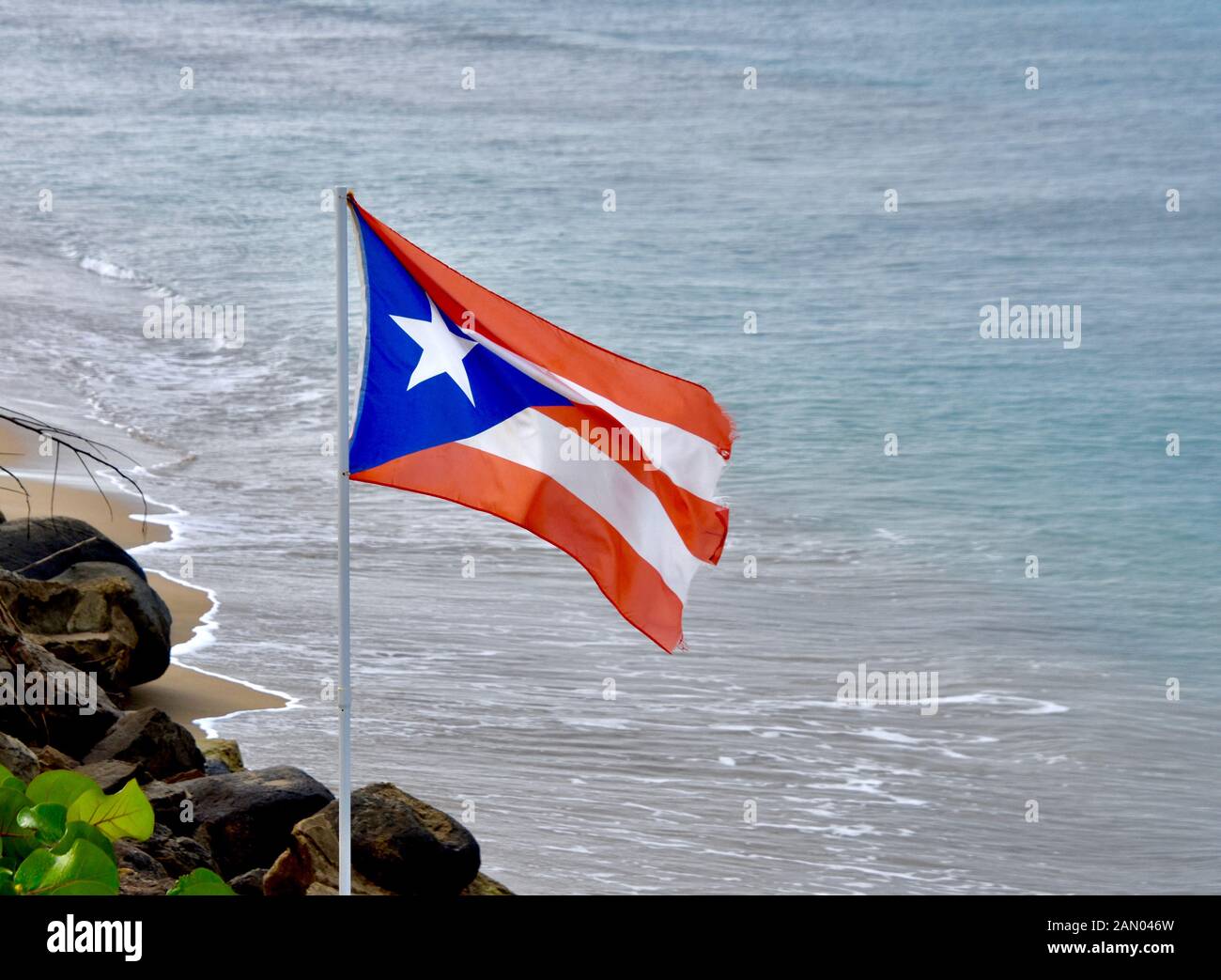 La bandiera di Puerto Rico vola su un oceano spiaggia di Rincon, PR. Copia dello spazio. Foto Stock