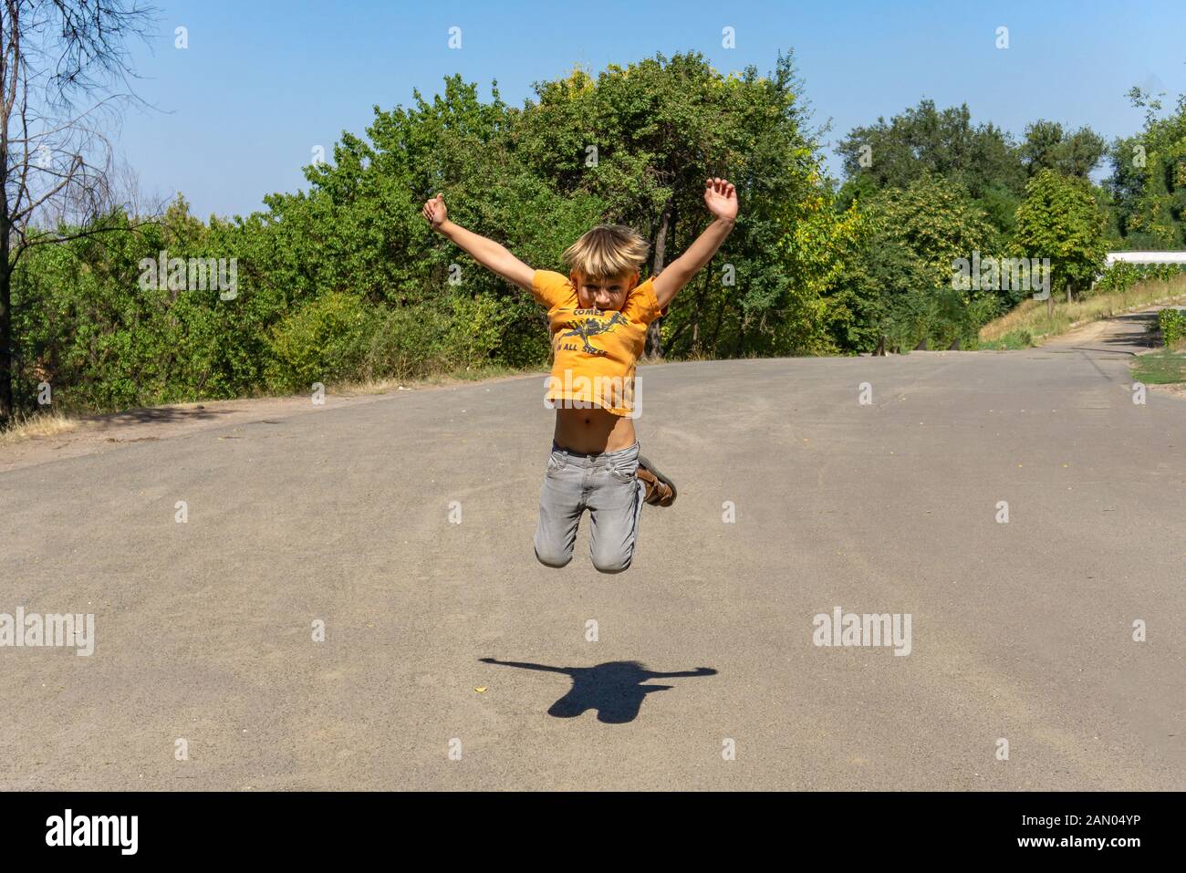 Il ragazzo gioioso e felice sta saltando sulla strada. Foto Stock