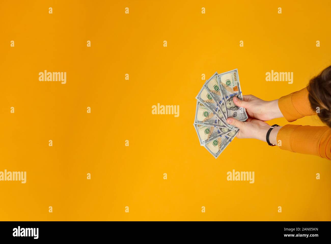 Mani femminili tenere le fatture del dollaro nelle loro mani, su uno sfondo giallo. Foto Stock