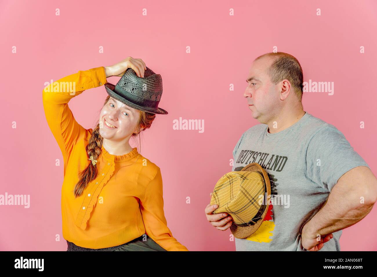 Un uomo e una donna in un cappello di paglia su uno sfondo di colore rosso in posa per la telecamera in studio. Foto Stock