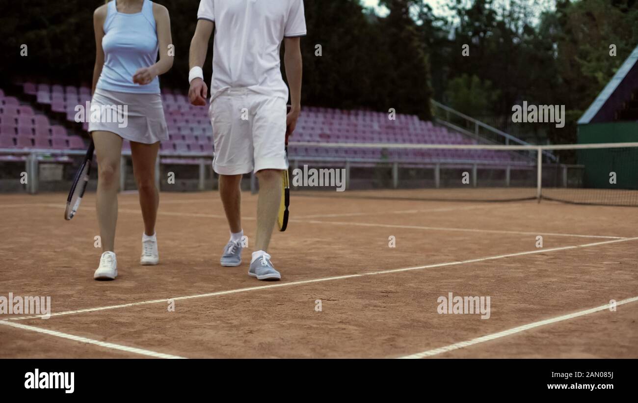 Giovani giocatori di tennis maschi e femmine che camminano sul campo, dopo la partita, da vicino Foto Stock