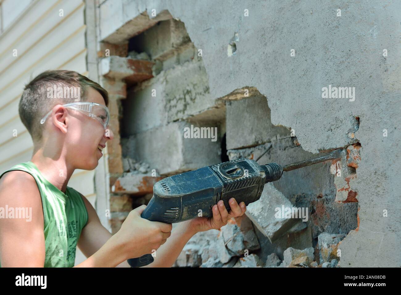 Un uomo con un jackhammer rende una apertura nella parete. Foto Stock