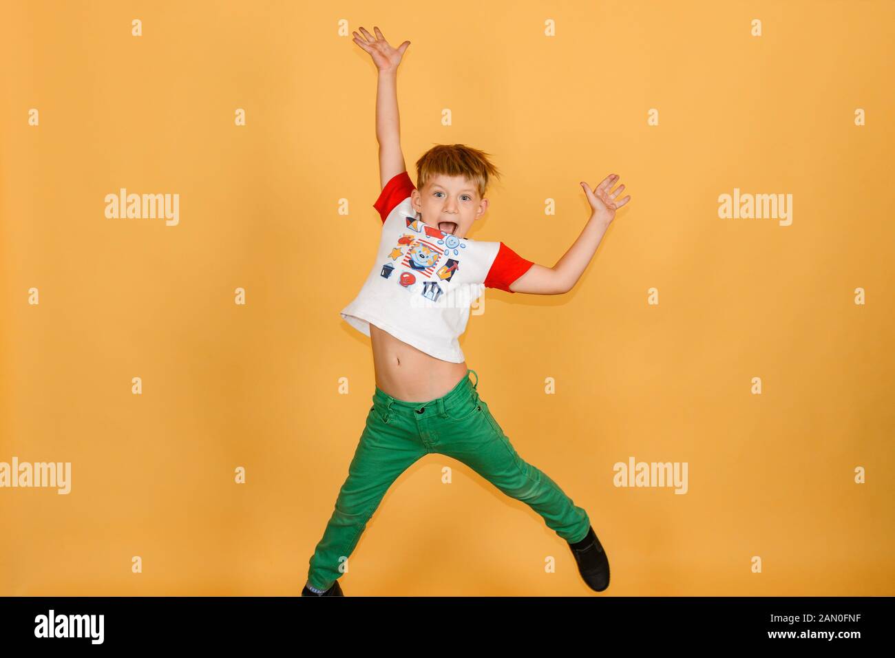 Una allegra e gioiosa del ragazzo è saltare su uno sfondo giallo in studio. Foto Stock