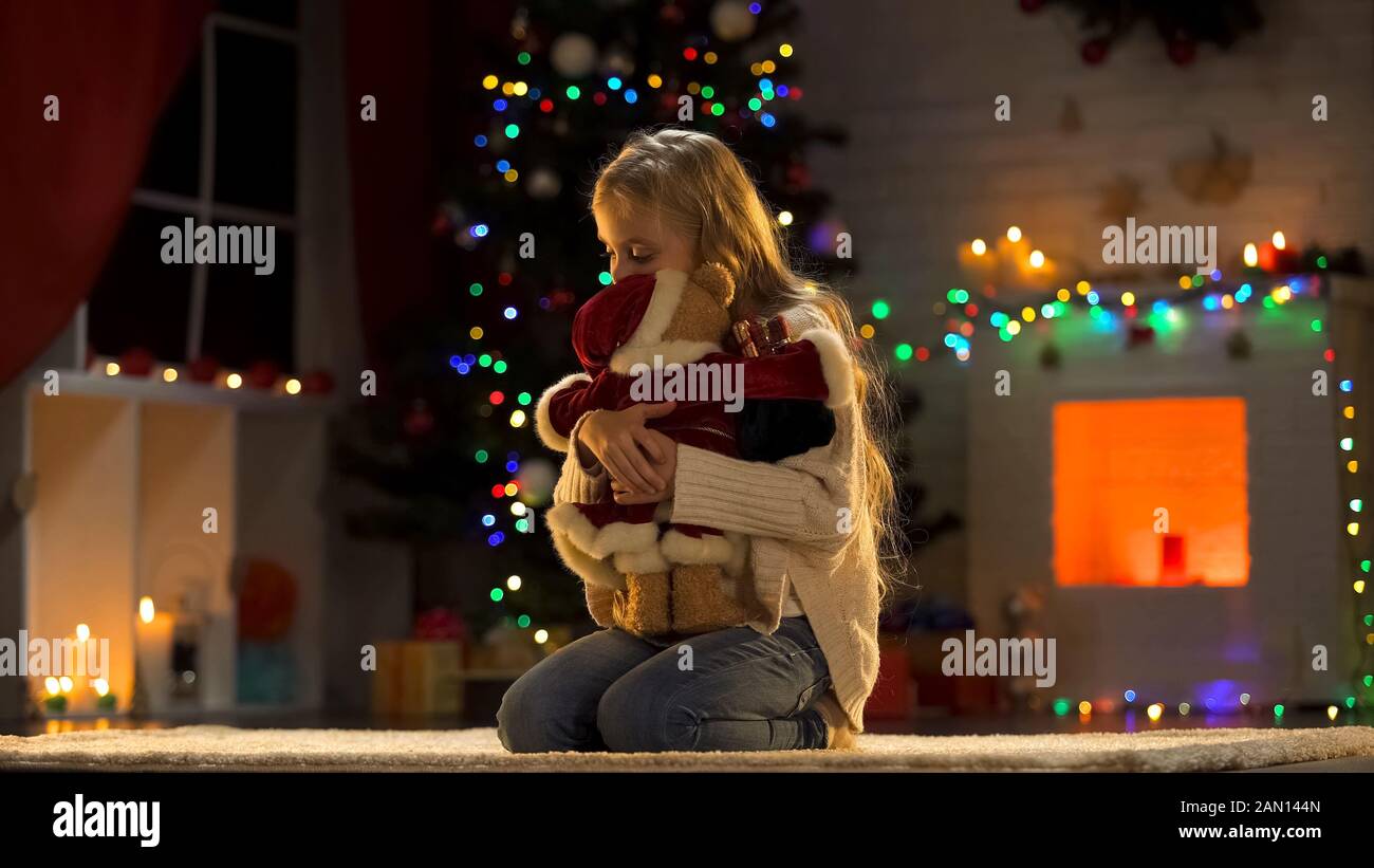 Ragazza sconvolta che abbraccia orsacchiotto, bambino abbandonato in orfanotrofio a Natale Foto Stock