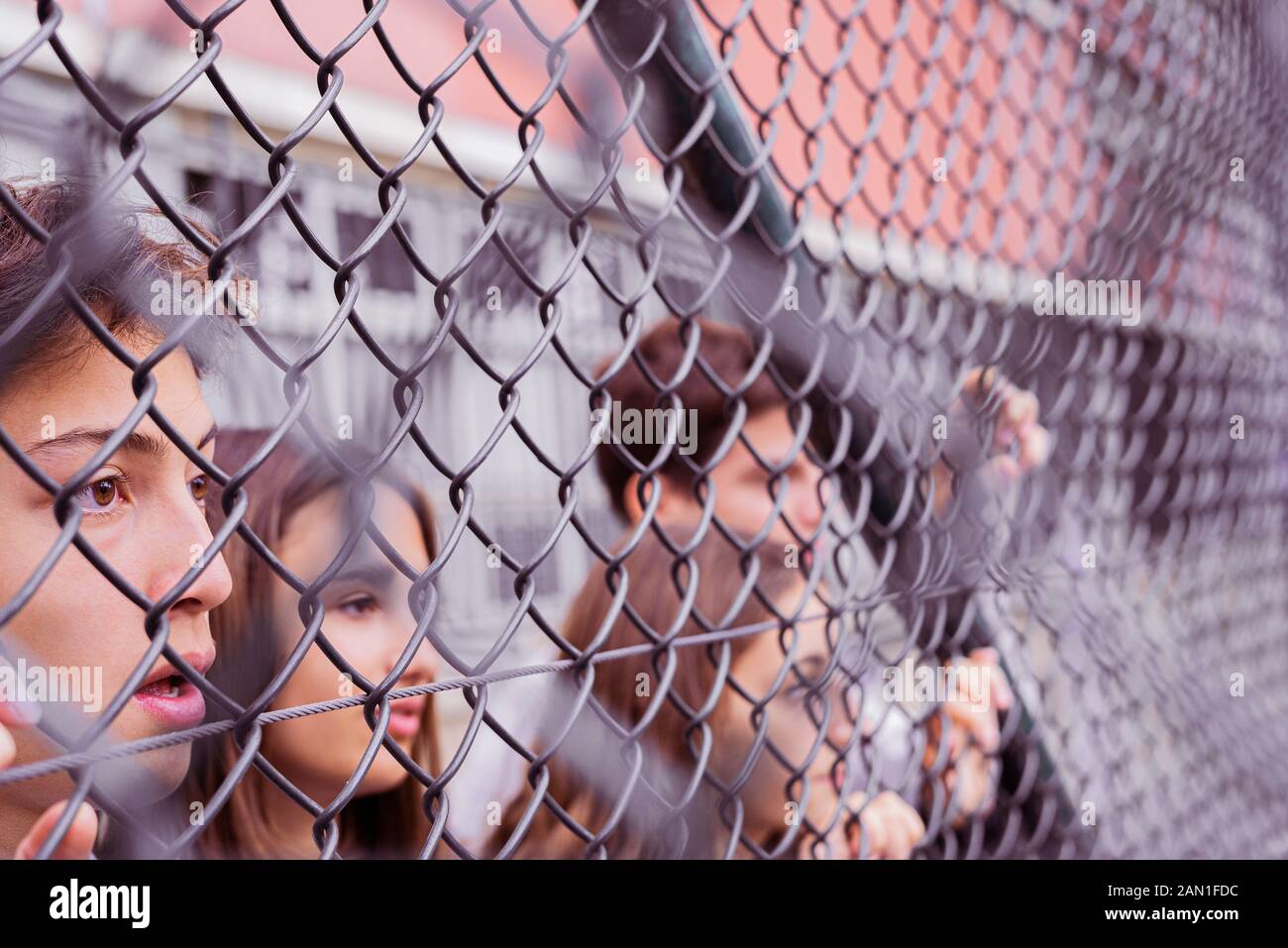 Amici che guardano attraverso catena-maglia recinzione Foto Stock