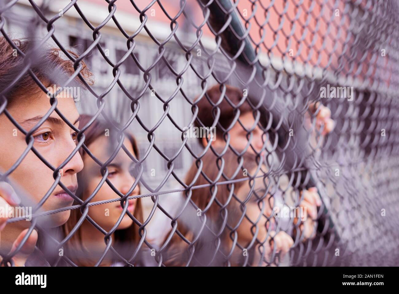 Amici che guardano attraverso catena-maglia recinzione Foto Stock