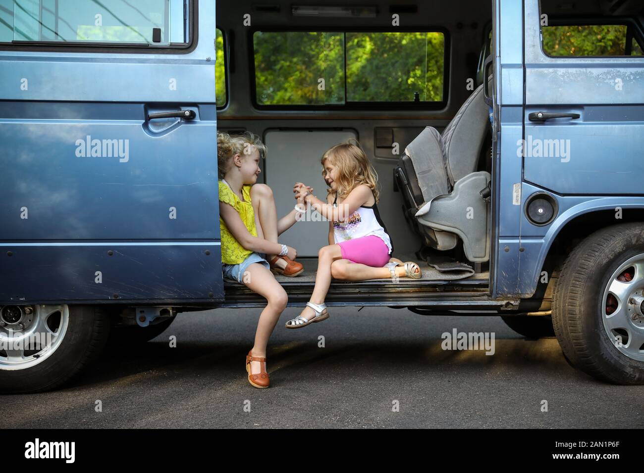 due ragazze che siedono nella porta di vecchia automobile d'epoca che tiene le mani Foto Stock