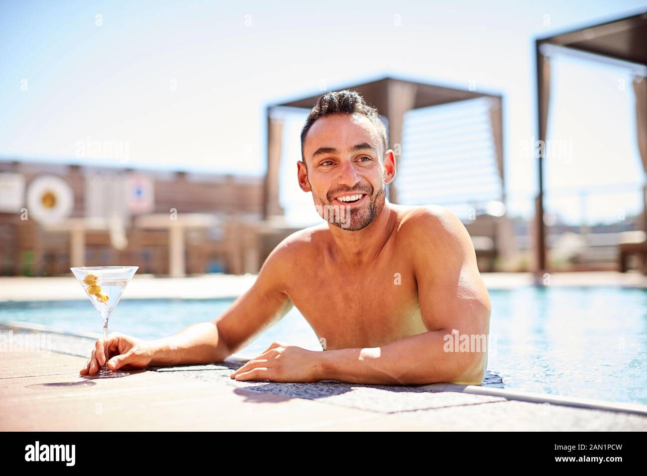 Un uomo che si gode un martini in piscina. Foto Stock