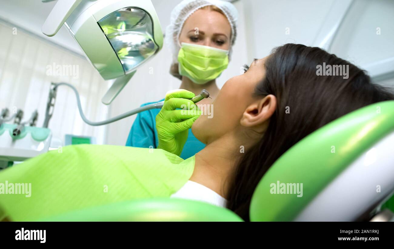 Foratura Stomatologist giovane donna dente, carie durante la procedura di rimozione, salute Foto Stock