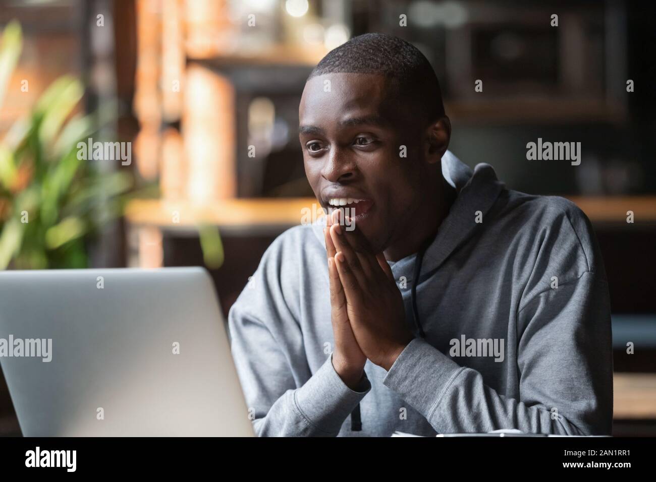 Il maschio nero eccitato si sente sorpreso leggendo le notizie del dio nella email Foto Stock