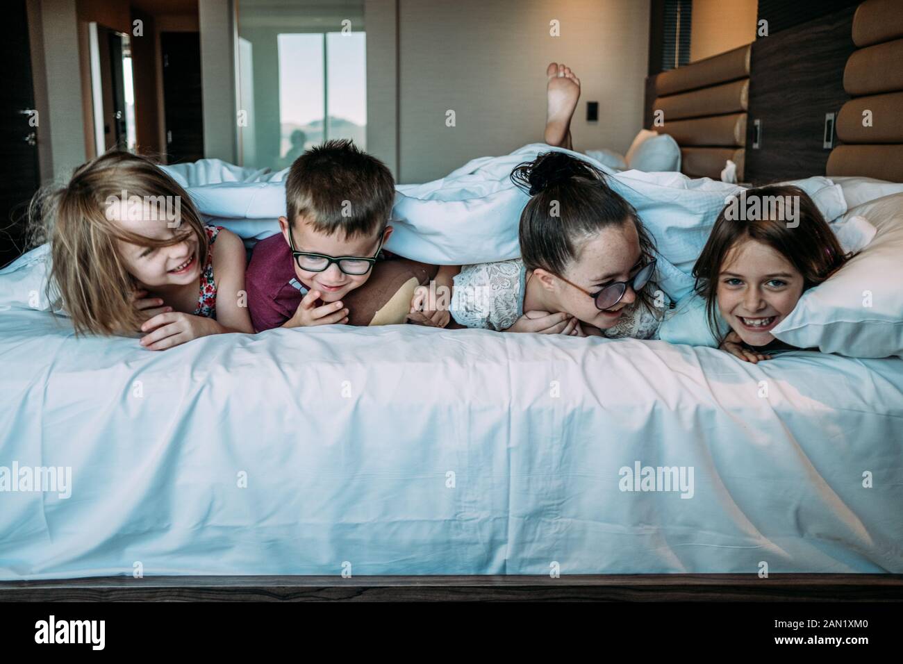 i bambini che si posano sul letto in camera d'albergo in vacanza Foto Stock