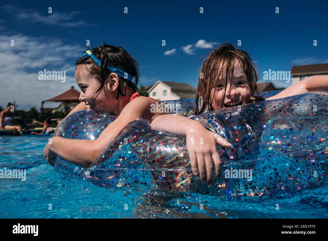 ragazze felici che giocano in piscina galleggiano insieme mentre nuotano Foto Stock