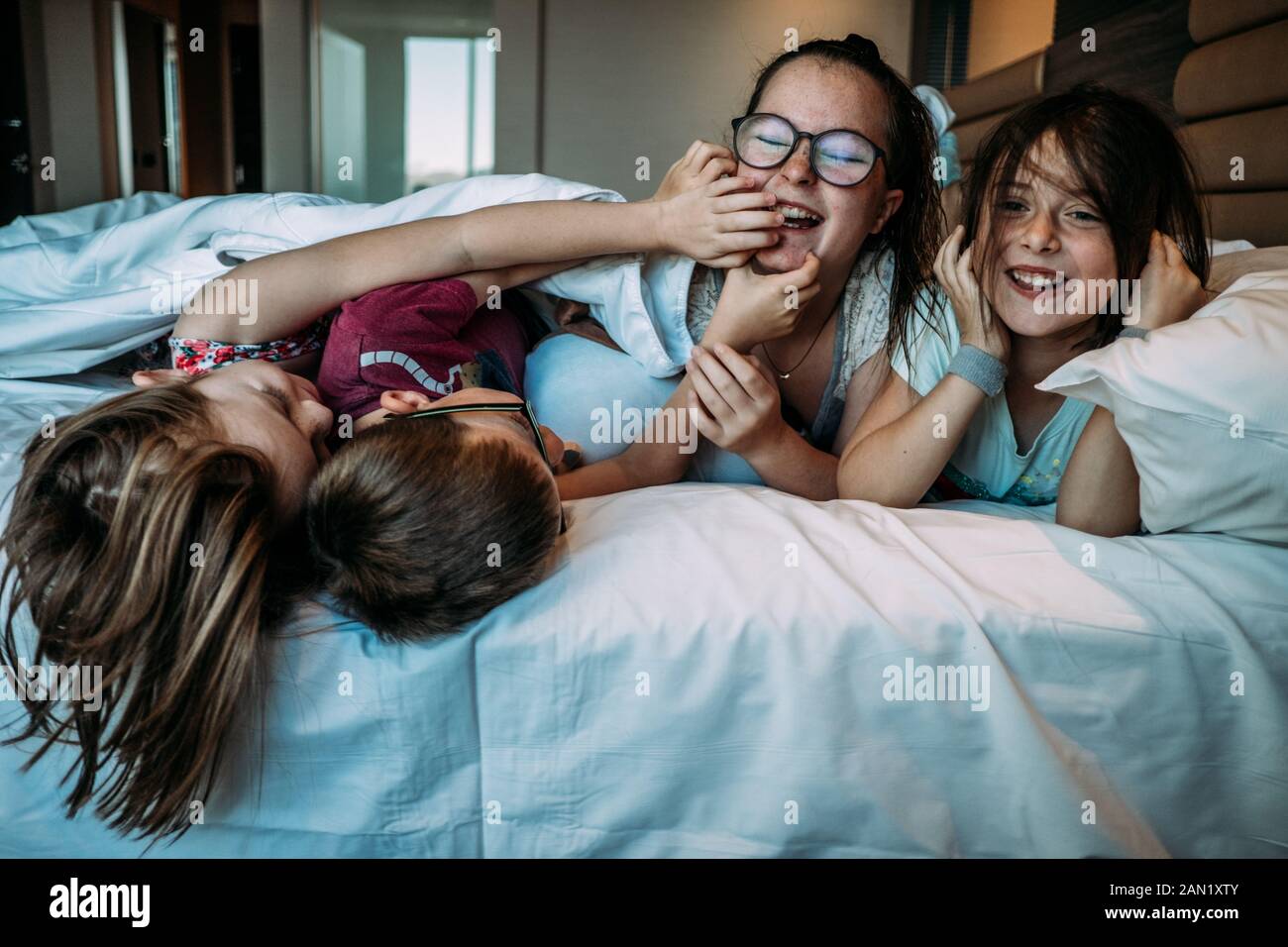 i bambini che giocano sul letto dell'hotel mentre sono in vacanza Foto Stock