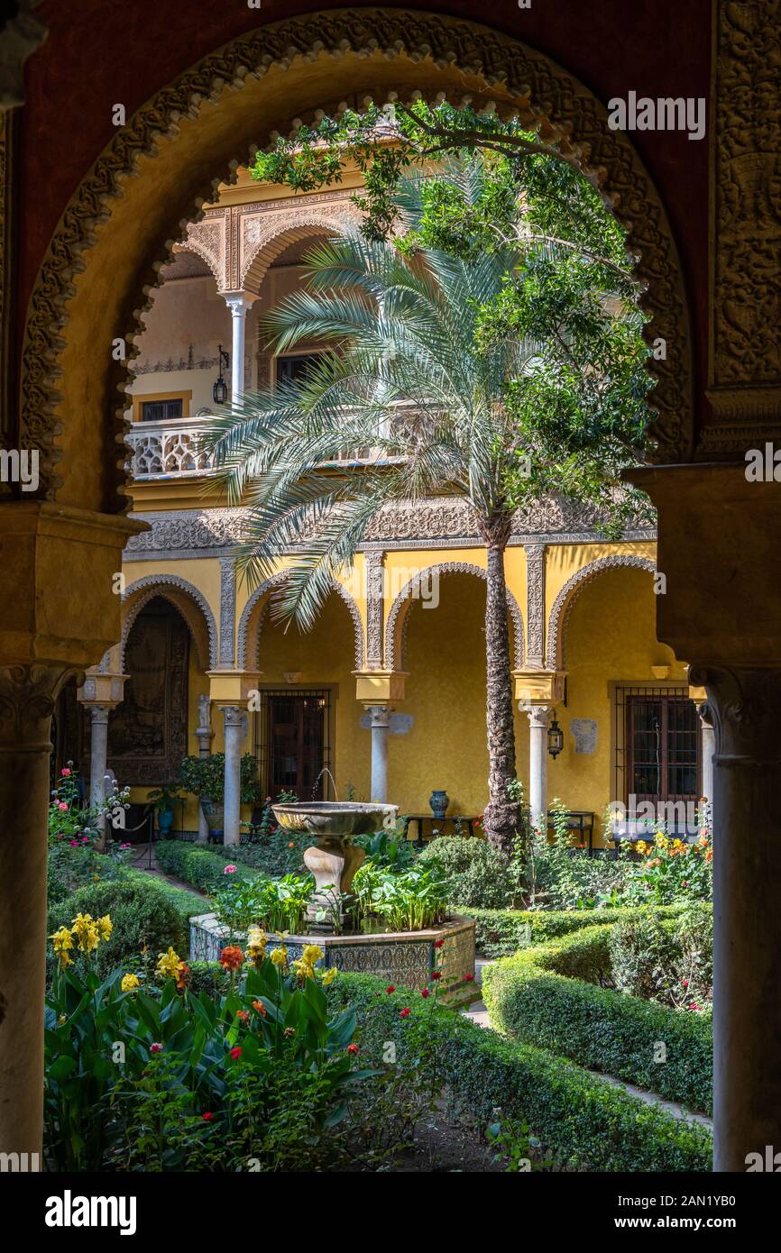 Il patio andaluso in stile Palm Tree Courtyard del Palacio de las Dueñas attraverso un arco Mudéjar decorato ornately Foto Stock