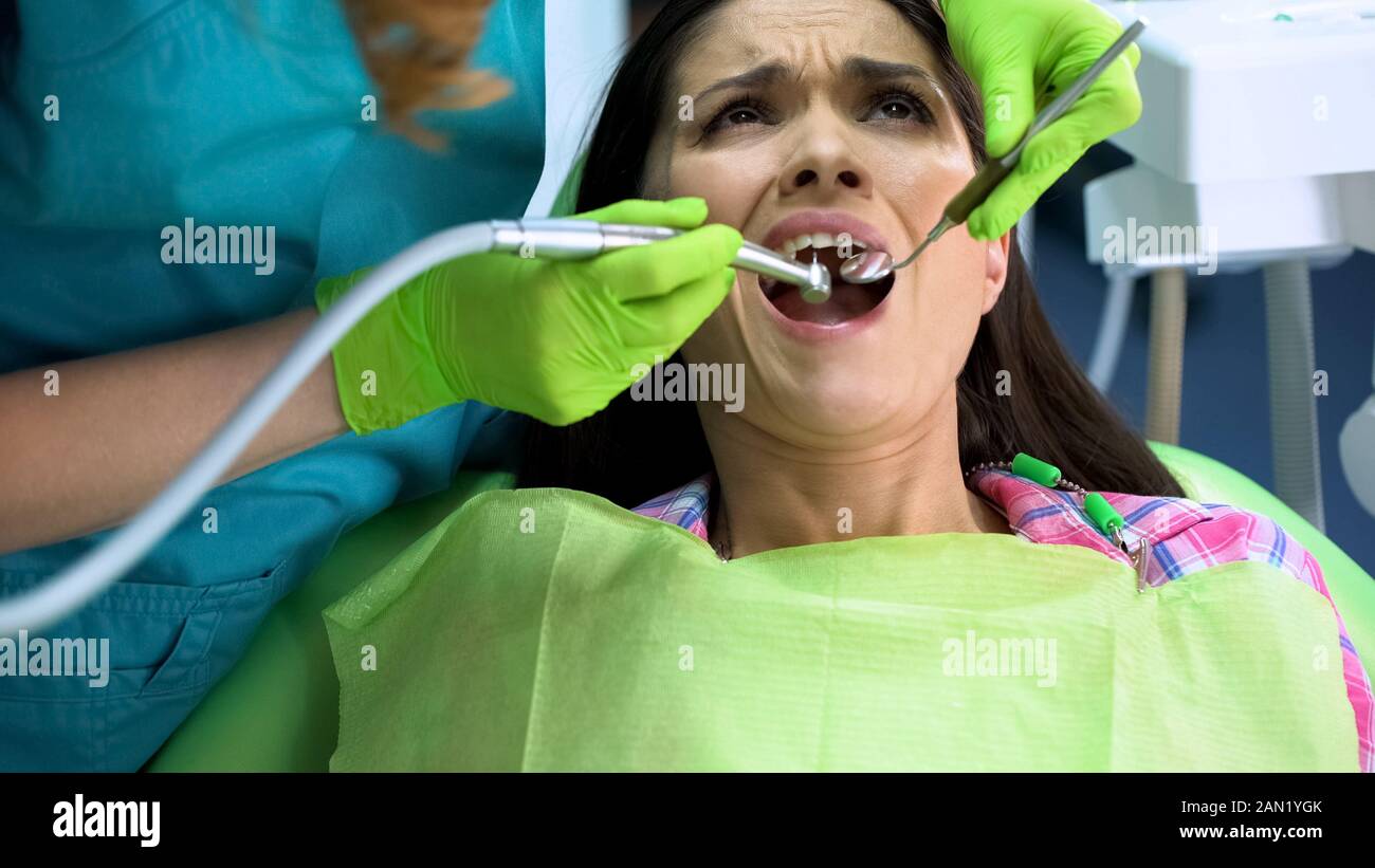 Femmina ansioso seduto nella sedia odontoiatria dopo la procedura di rimozione della carie Foto Stock