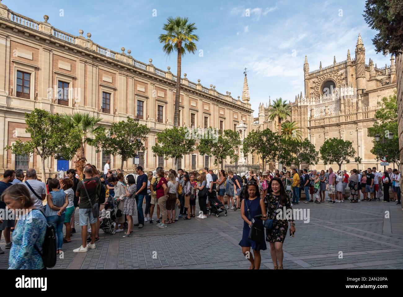 Le folle si accodano pazientemente all'ombra per entrare nel Palazzo reale Alcázar, sotto lo sfondo della cattedrale gotica di Siviglia. Foto Stock