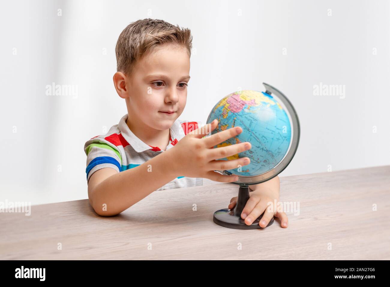 Ragazzo gira il mondo sulla scrivania. Boncept di apprendimento geografia e educazione dei bambini Foto Stock