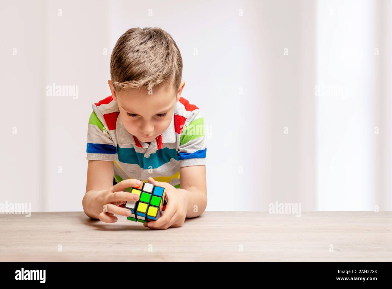Bambino risolve un cubo di Rubik. Concetto di speedcubing puzzle della concorrenza. Copia spazio accanto Foto Stock