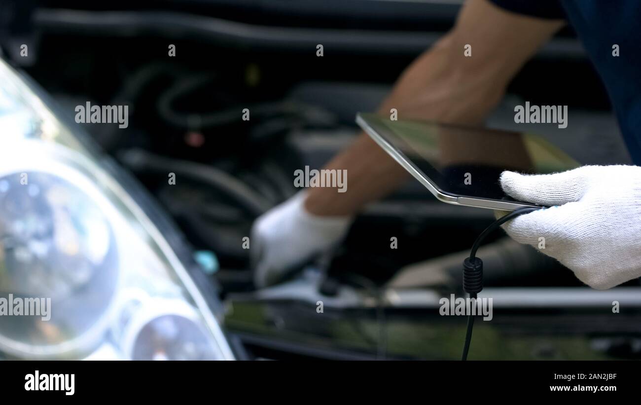 Auto diagnostica con tecnologie informatiche, ingegnere utilizza tablet per la riparazione auto Foto Stock