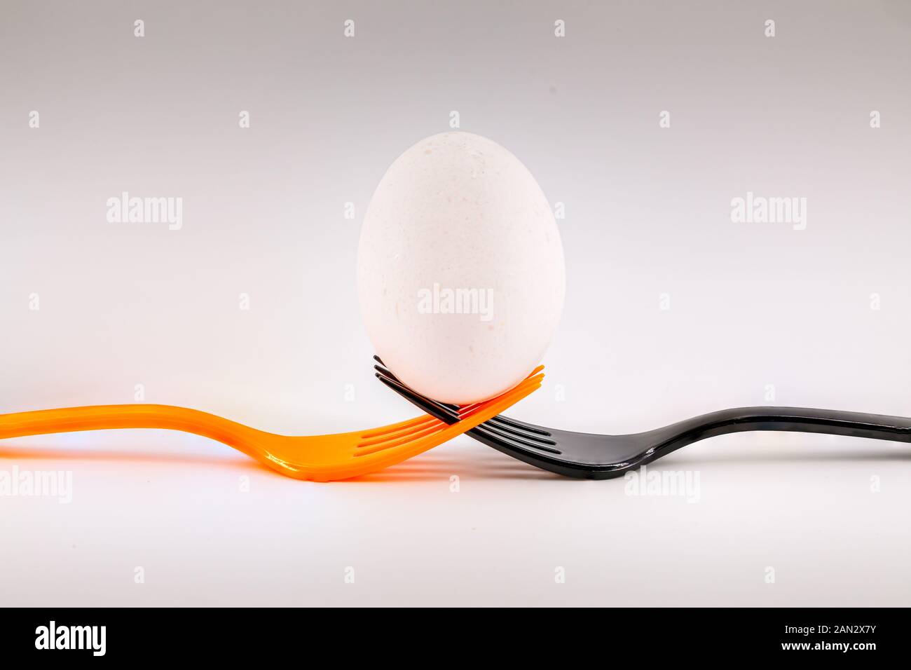 Un nero e un'arancia forcella tenendo un uovo. Concetto inclusionary teamwork Foto Stock