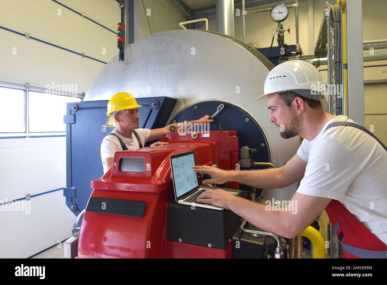 Riparazione meccanica di una macchina in un moderno impianto industriale - la professione e il lavoro di squadra Foto Stock