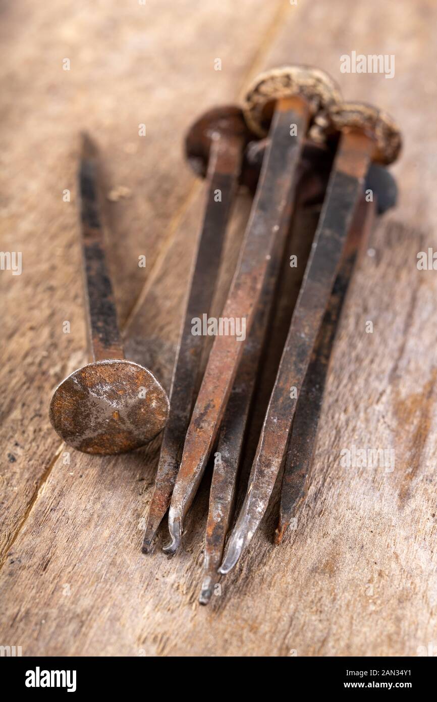 Vecchi chiodi arrugginiti su un banco di lavoro. Elementi in acciaio forgiato nella vecchia tecnologia per la giunzione di legno. Luogo - laboratorio di falegnameria. Foto Stock