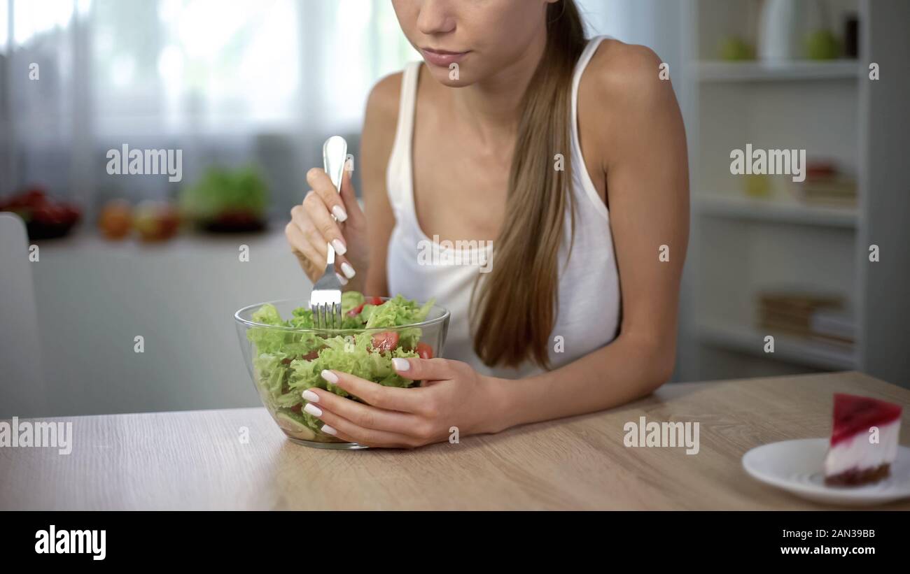 Slim ragazza sceglie invece di insalata di torta, sana dieta bilanciata, autodisciplina Foto Stock