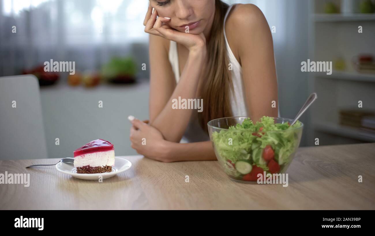 Femmina Slim scegliendo tra la torta e insalata, dieta sana vs alto-caloria cibo Foto Stock