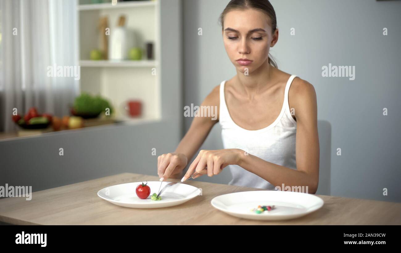 Ragazza mangia gli spinaci, guarda a anti-obesità pillole, farmaci come un modo semplice per perdere peso Foto Stock
