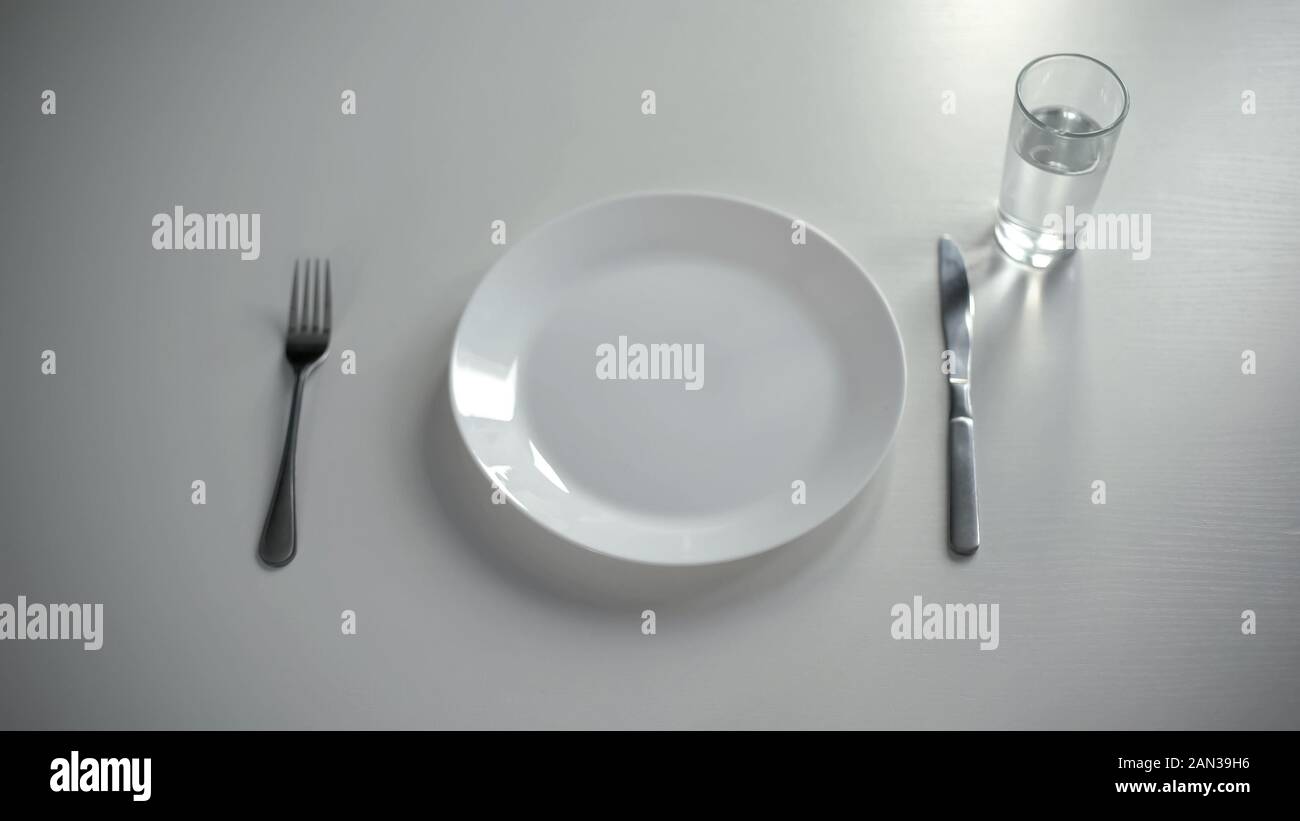 Piastra vuota serviti al tavolo, vetro con acqua né denaro per il cibo, la povertà Foto Stock