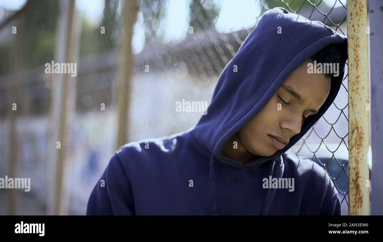 Sconvolto boy appoggiata sul recinto, migrante bambino separato dalla famiglia e detenuti Foto Stock