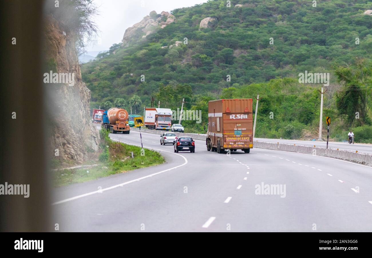 Private e dei veicoli commerciali il movimento verso l'alto tra due colline in una sei corsie Autostrada nazionale in India, efficiente e sicuro trasporto terrestre Foto Stock