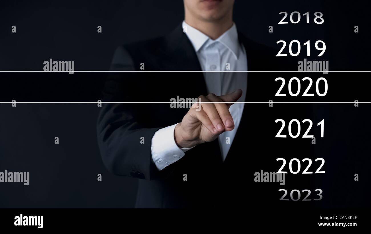 Imprenditore seleziona 2020 anno nel menu virtuale, ricerca di dati, business history Foto Stock