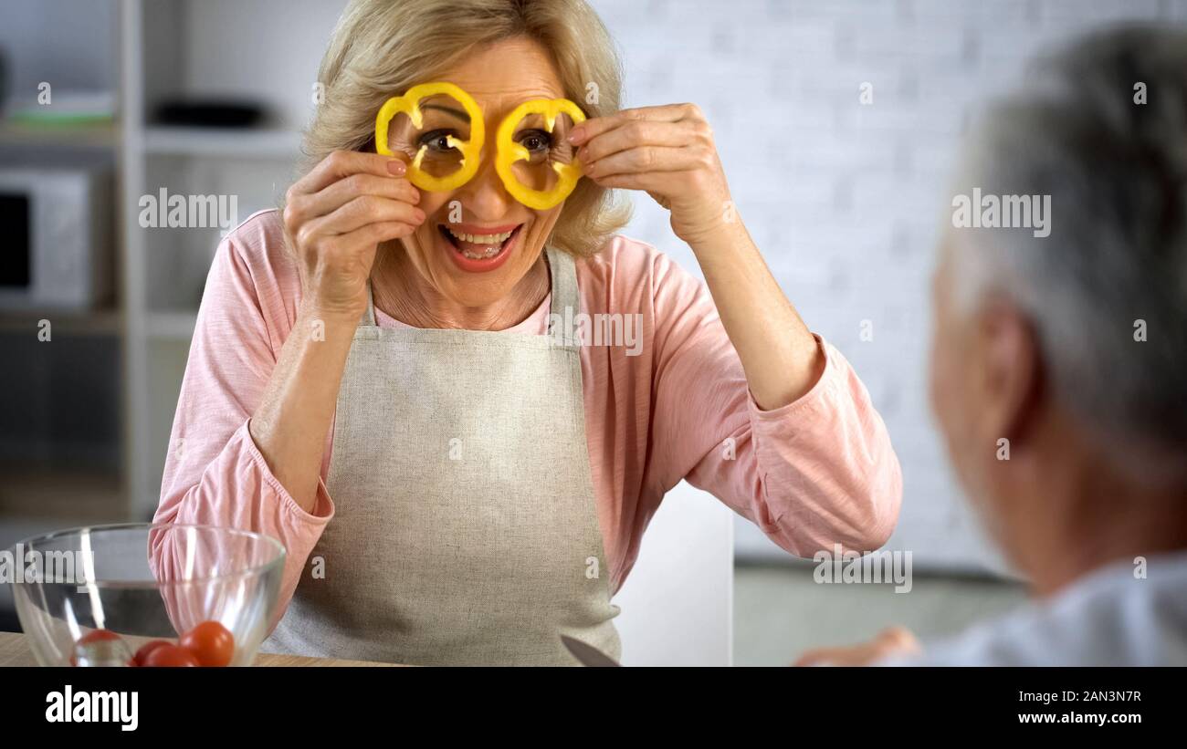 Moglie di positivo nel grembiule azienda pepe fette davanti agli occhi, cucina hobby, salute Foto Stock