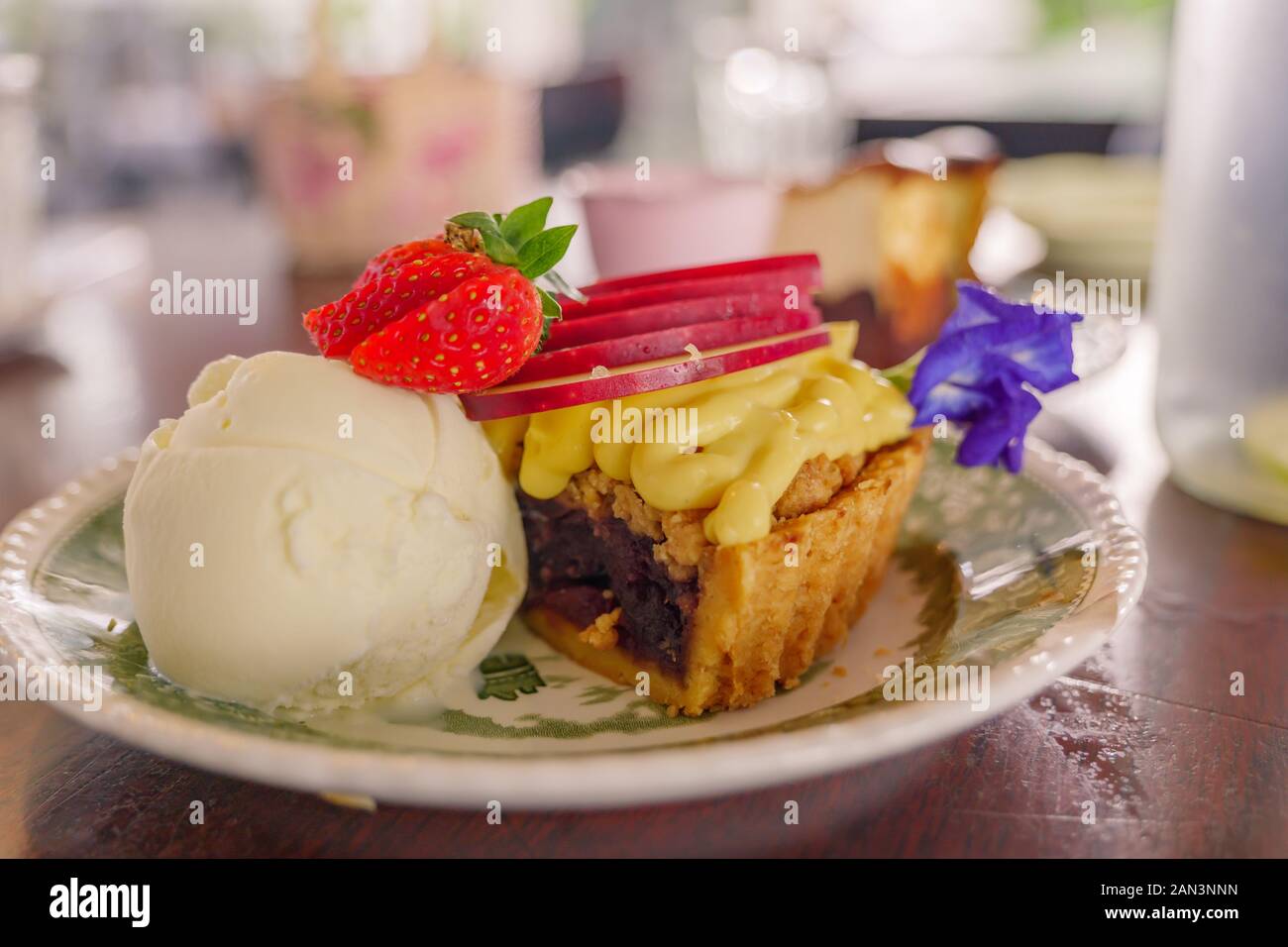 Vista della torta di mele crumble torta di frutti di bosco con gelato alla vaniglia in cima con fragola. Foto Stock