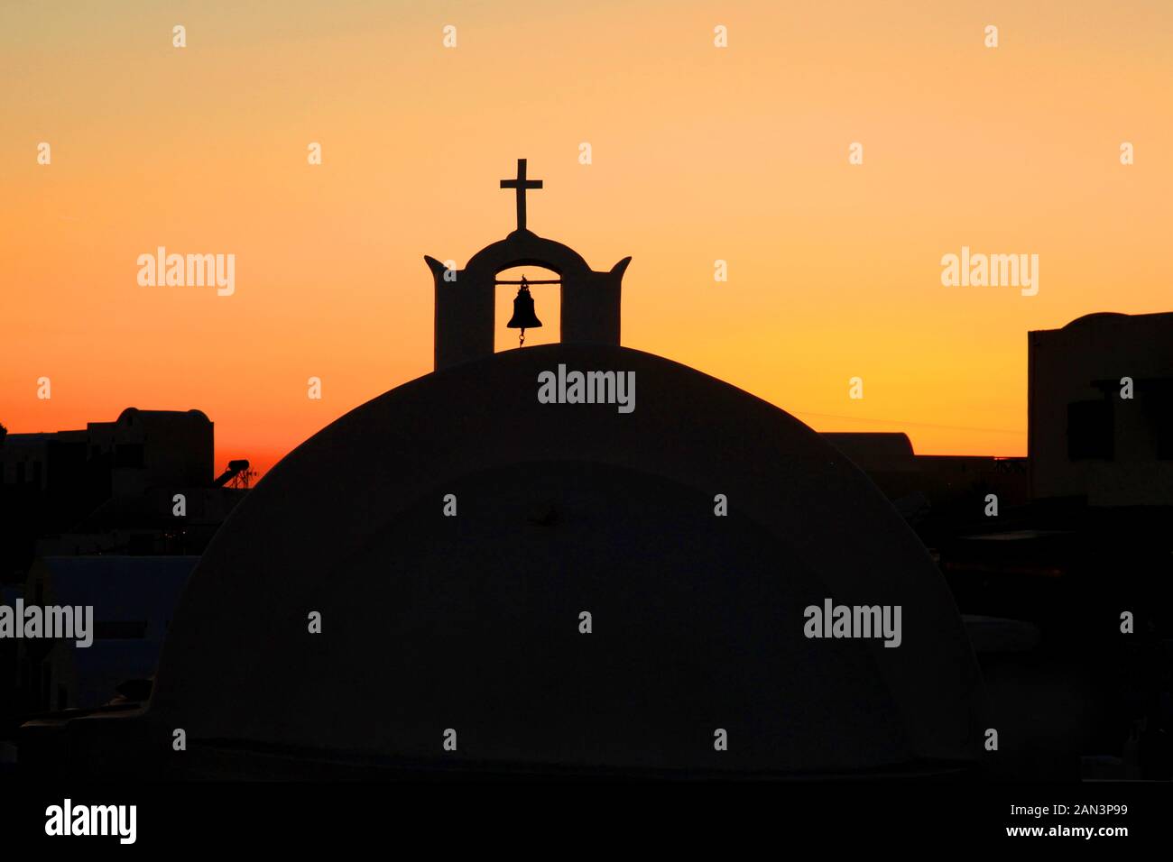 Una cupola della chiesa con campana e croce religiosa nella città di Oia a Santorini, Grecia. Foto Stock