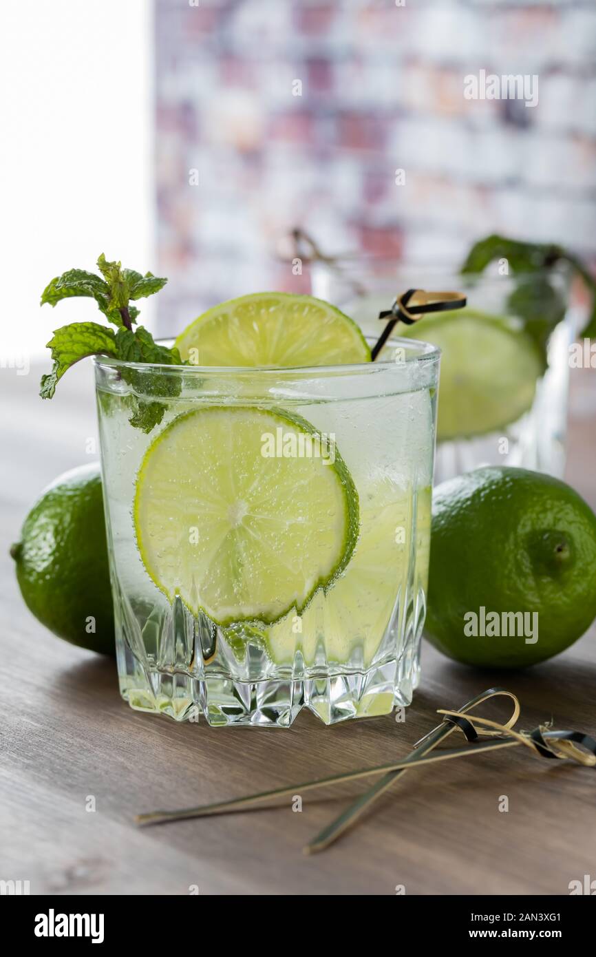 In prossimità della vista di un bicchiere di acqua frizzante con lime e menta guarnire. Foto Stock