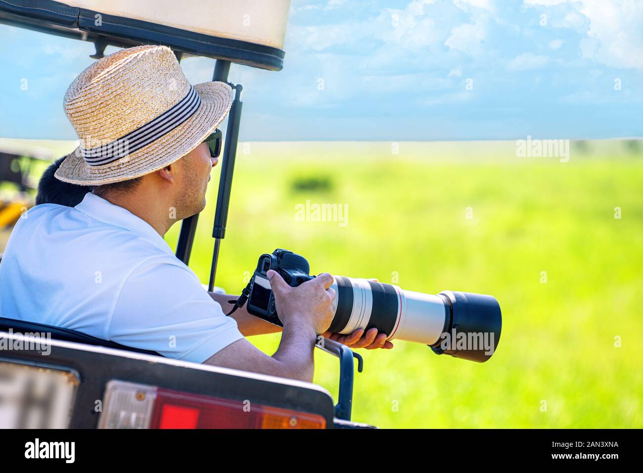 L'uomo fotografo scatta una foto con la fotocamera professionale dal veicolo turistico su safari tropicale. Fotografia della fauna selvatica in Kenya e Tanzania. Foto Stock