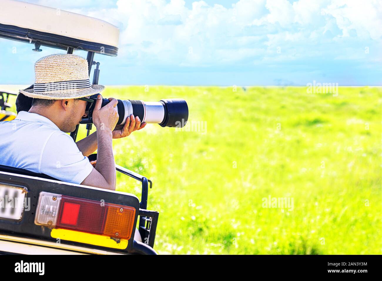 L'uomo fotografo scatta una foto con la fotocamera professionale dal veicolo turistico su safari tropicale. Fotografia della fauna selvatica in Kenya e Tanzania. Foto Stock