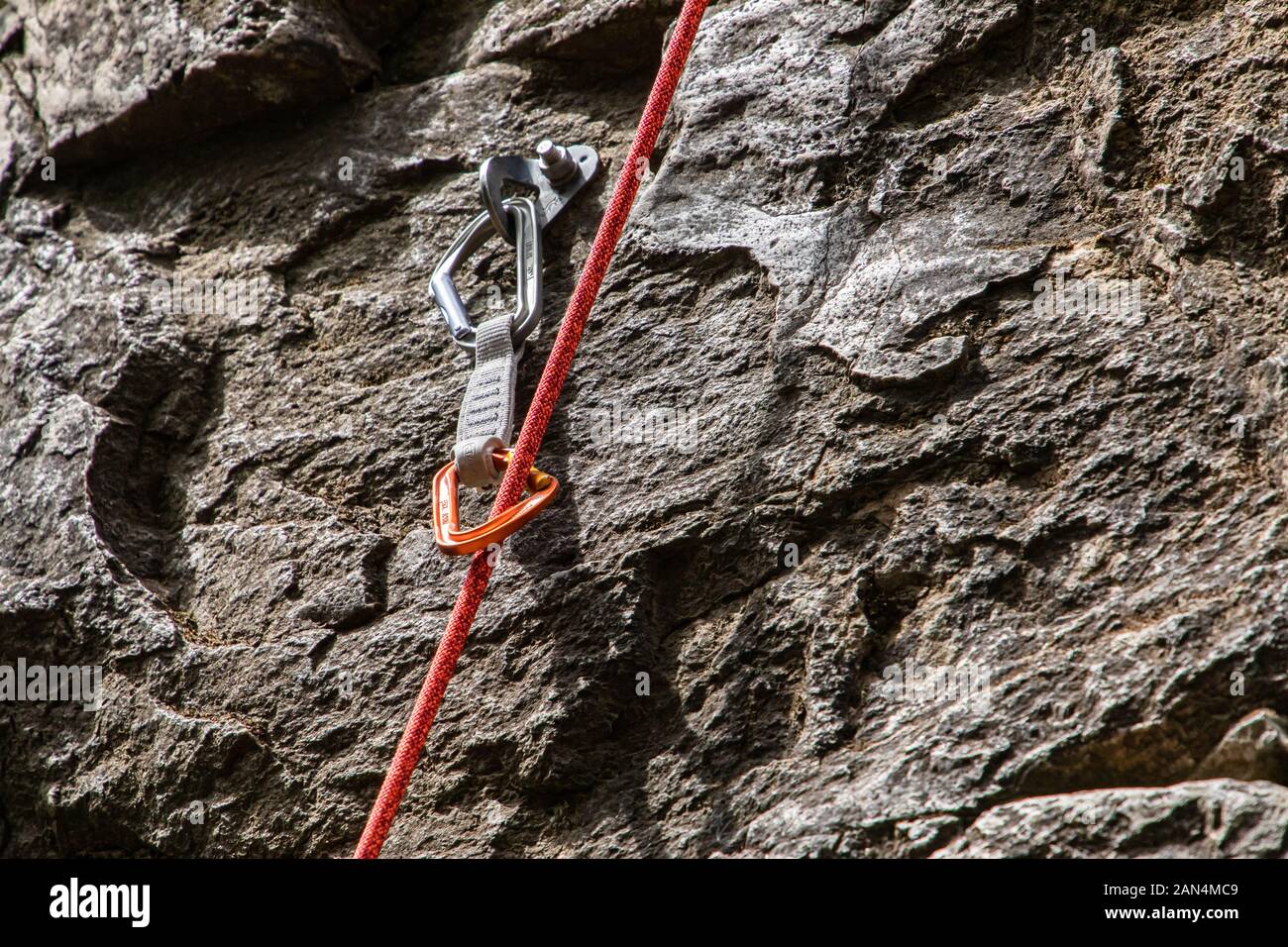 Una chiusura e una vista dettagliata di una sosta del dispositivo e corda dinamica fissata ad un robusto roccia calcarea. Professional arrampicata attrezzature in uso Foto Stock