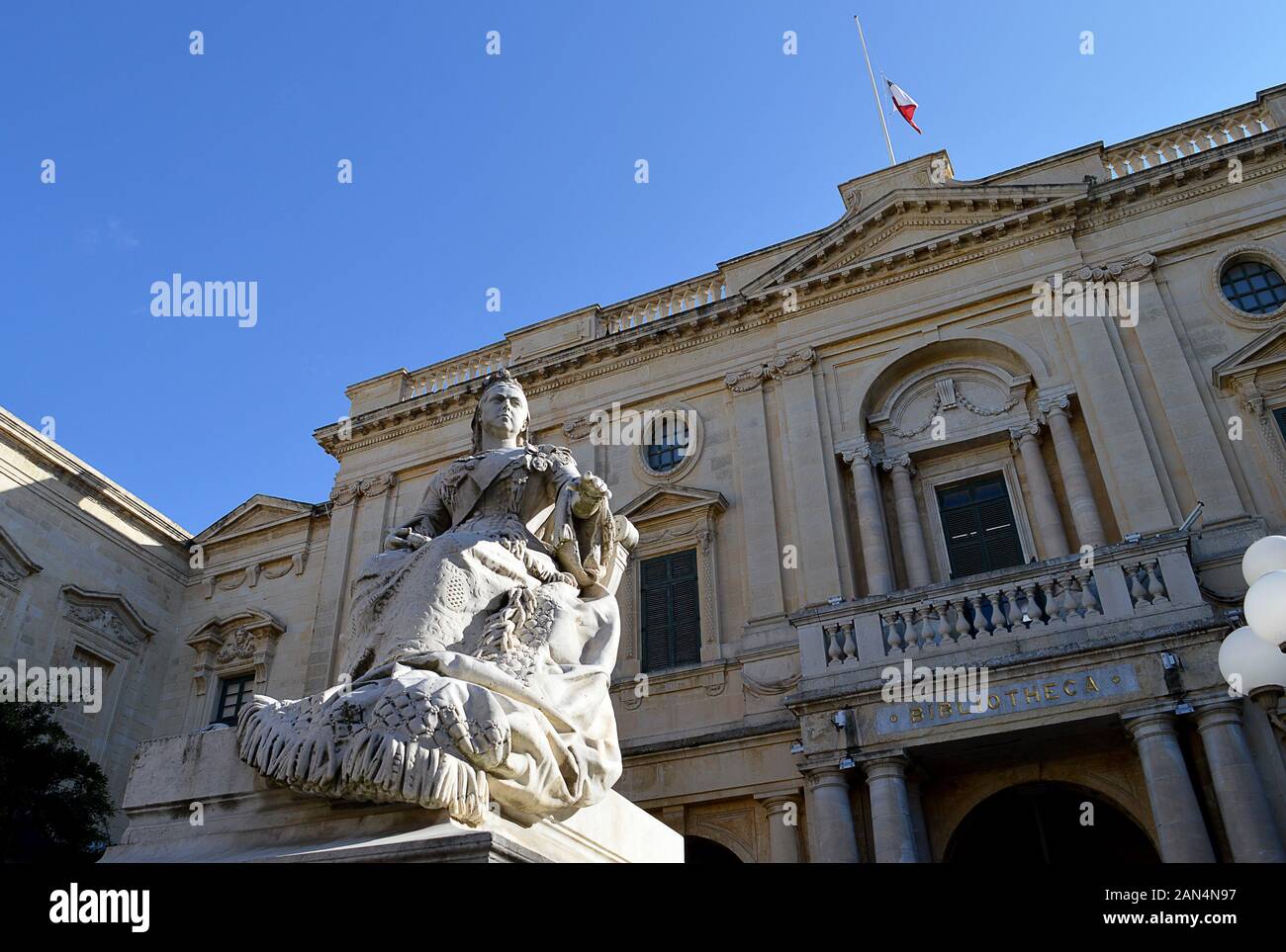 Un 1891 statua della regina Victoria sorge di fronte alla biblioteca, la Biblioteca Nazionale di Malta, in Piazza della Repubblica, Valletta, Malta Foto Stock