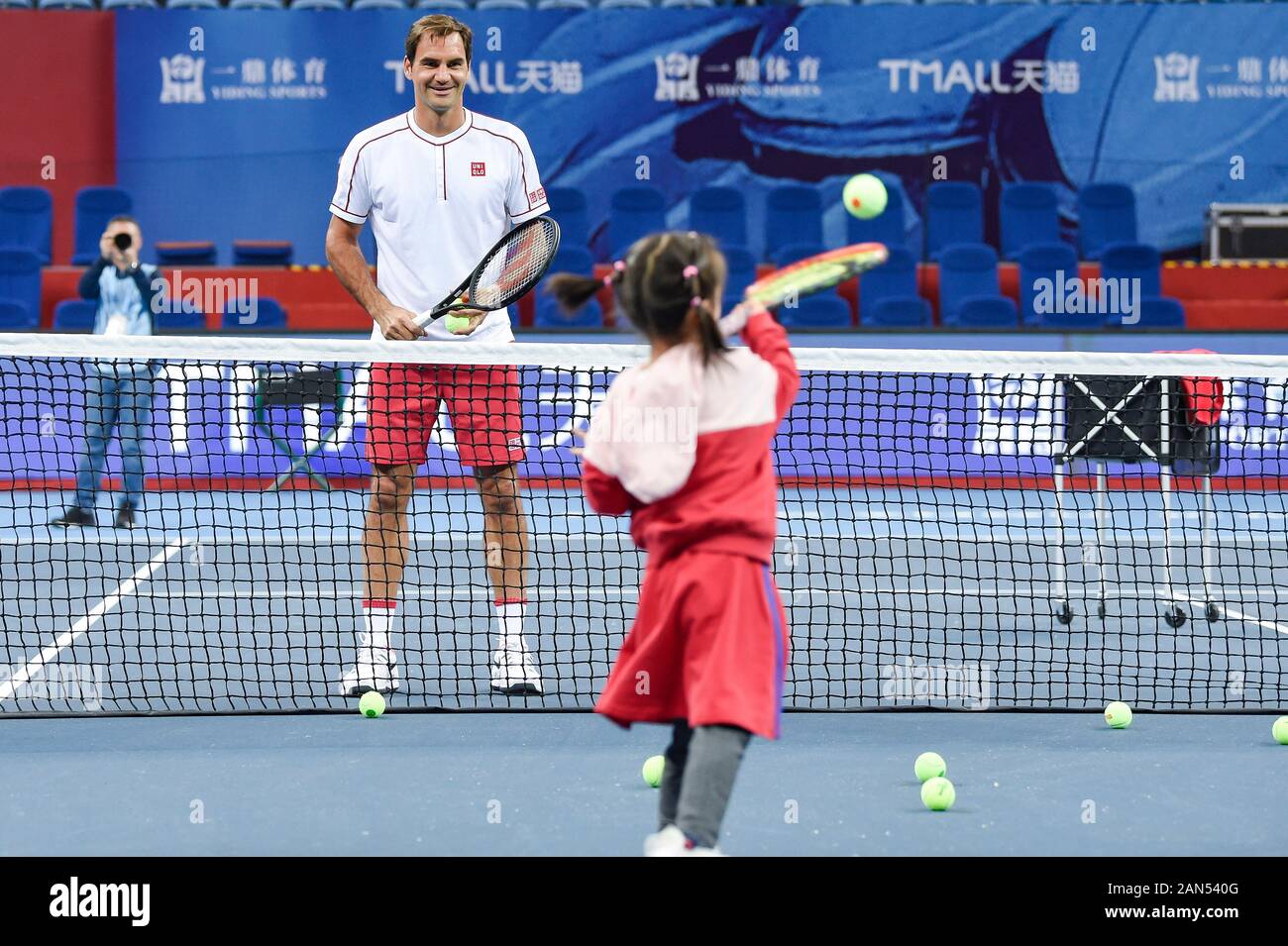 Swiss professional giocatore di tennis Roger Federer, sinistra, gioca a tennis con piccole fans durante la sua formazione, Hangzhou, est della Cina di provincia dello Zhejiang Foto Stock