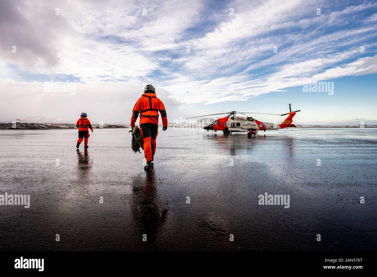 Coast Guard Base Kodiak ausili alla navigazione (ATON) organi di servizio a piedi verso un MH-60 elicottero Jayhawk nella baia di freddo, Alaska. La ATON membri distribuire a bordo di elicotteri per funzionamento in avanti posizioni intorno all'Alaska per la riparazione e la manutenzione di navigazione marittima aids. L'elicottero equipaggi sono di vitale importanza per ottenere questi ATON i membri a più postazioni remote che non sono accessibili tramite la barca. Stati Uniti Coast Guard foto di Sottufficiali di prima classe Bradley Pigage. Foto Stock