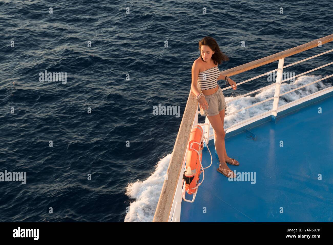 Asian teen nel tubo superiore e shorts in piedi sul ponte blu accanto a  orange salvagente sul traghetto andando a Lesbo Foto stock - Alamy