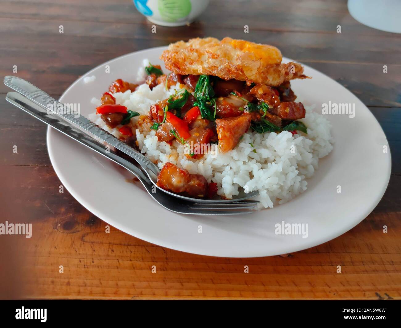 La croccante maiale ventre con basilico tailandese e uovo fritto sul riso Foto Stock