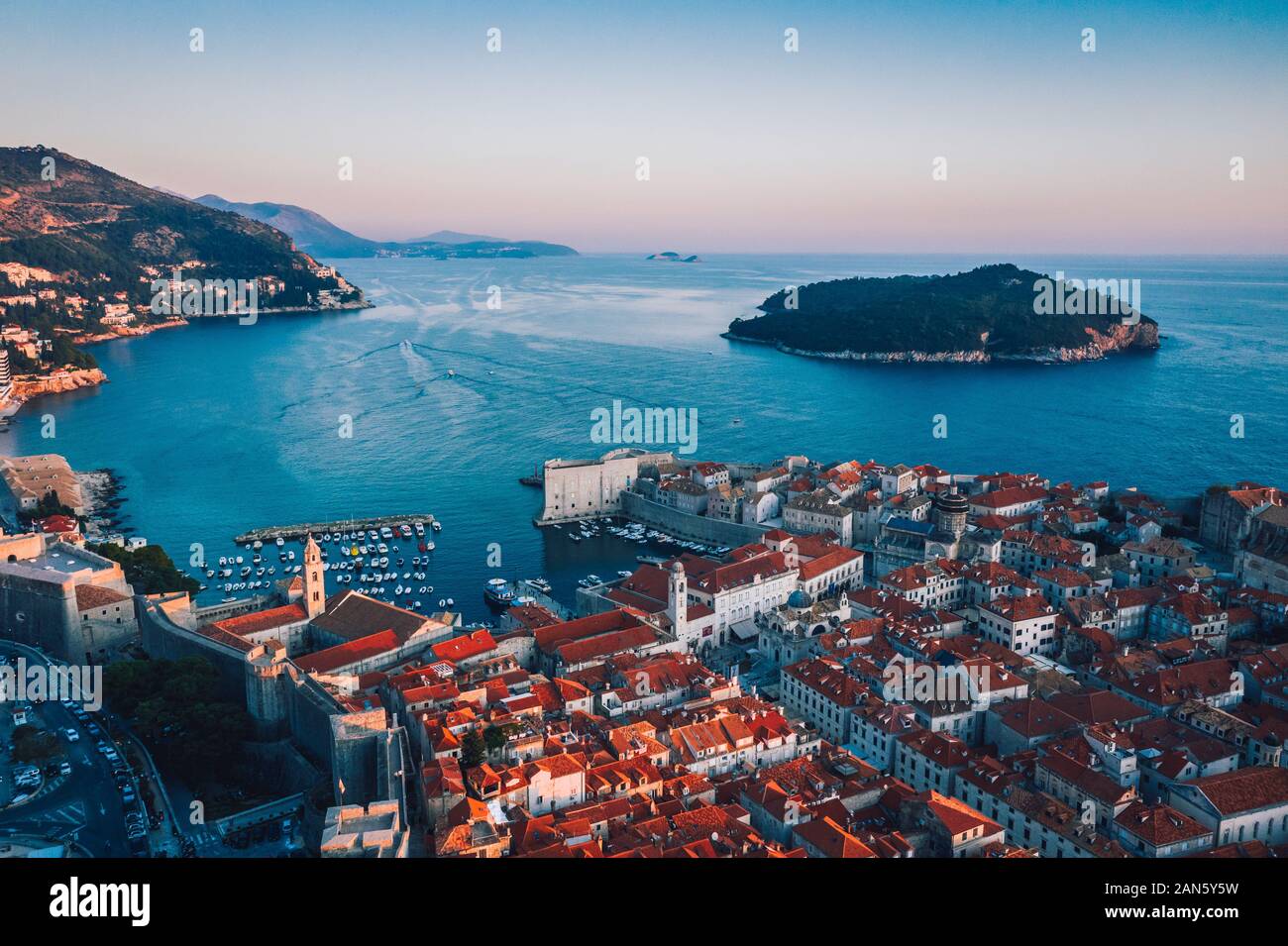 Veduta aerea del drone sulla costa croata che rivela la città vecchia di Dubrovnik e l'isola di Lokrum al tramonto. Città vecchia europea e mare Adriatico. Foto Stock