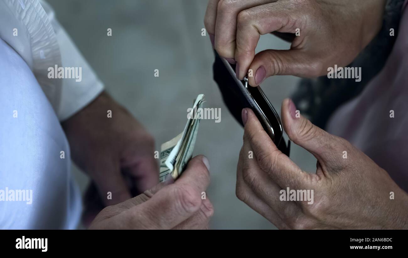 Cura il marito di mettere le banconote di dollari in portafoglio femmina, supporto e amore Foto Stock