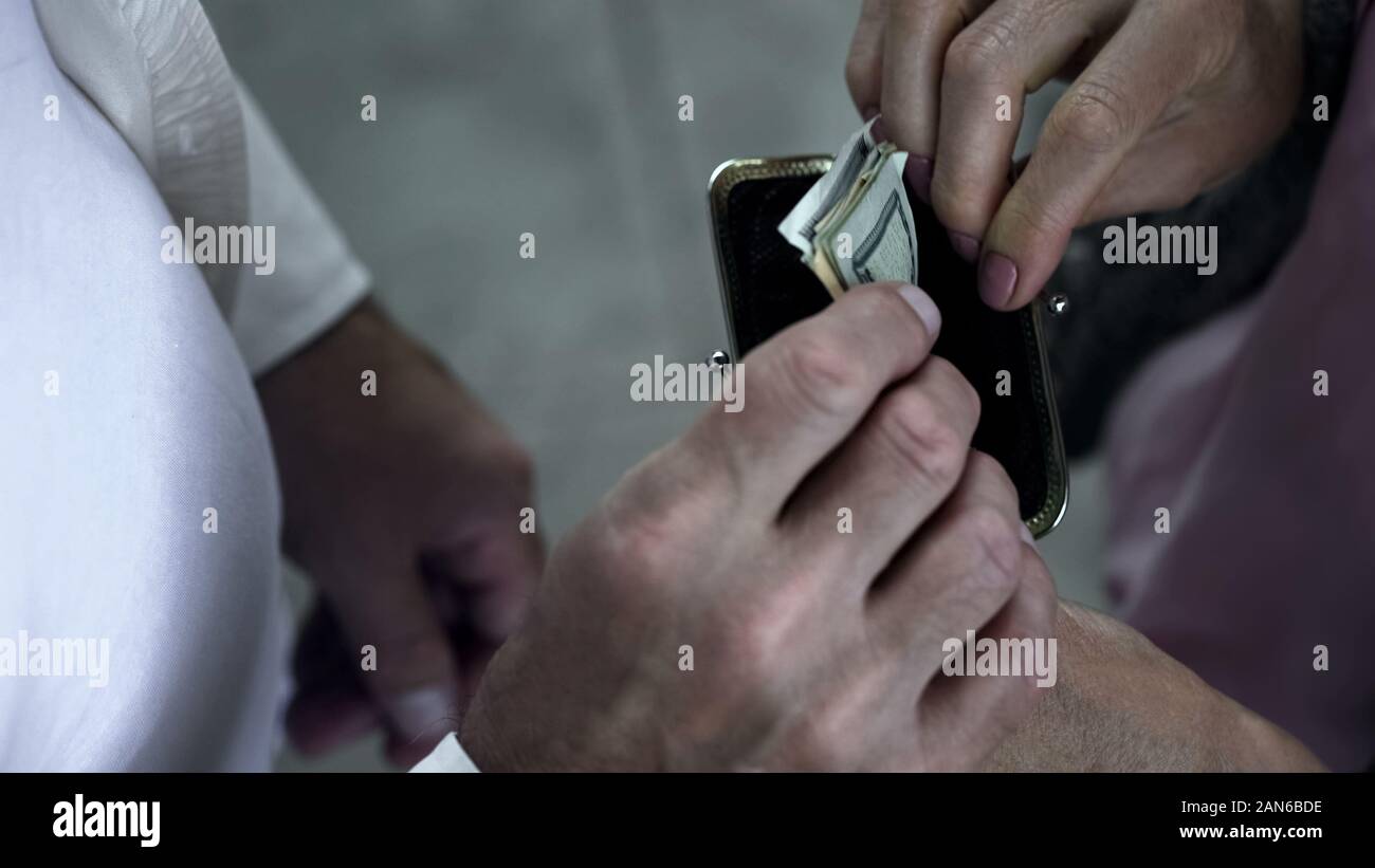 Caring figlio di mettere le banconote di dollari in madre wallet, supporto e amore, primo piano Foto Stock
